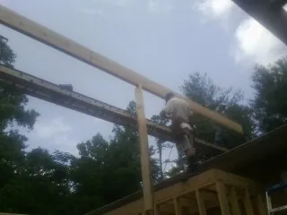 Carpenter setting a ridge beam over a new addition frame — Ice Dam Removal by Roofing Brothers in Camby