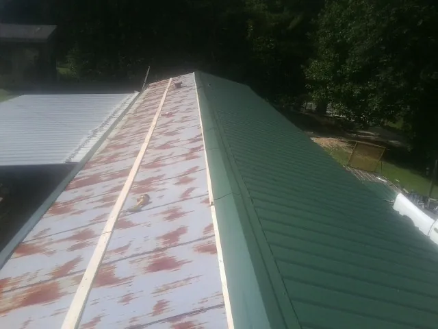 Old rusted panels beside newly installed green metal roofing — Wind Damage Roof Repair by Roofing Brothers in Camby