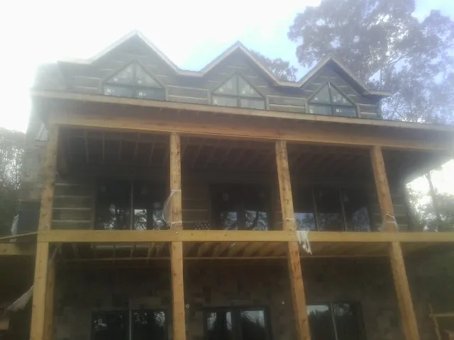 Dormers and porch framing on a large log home under construction — Roof Coating work by our crew in Camby