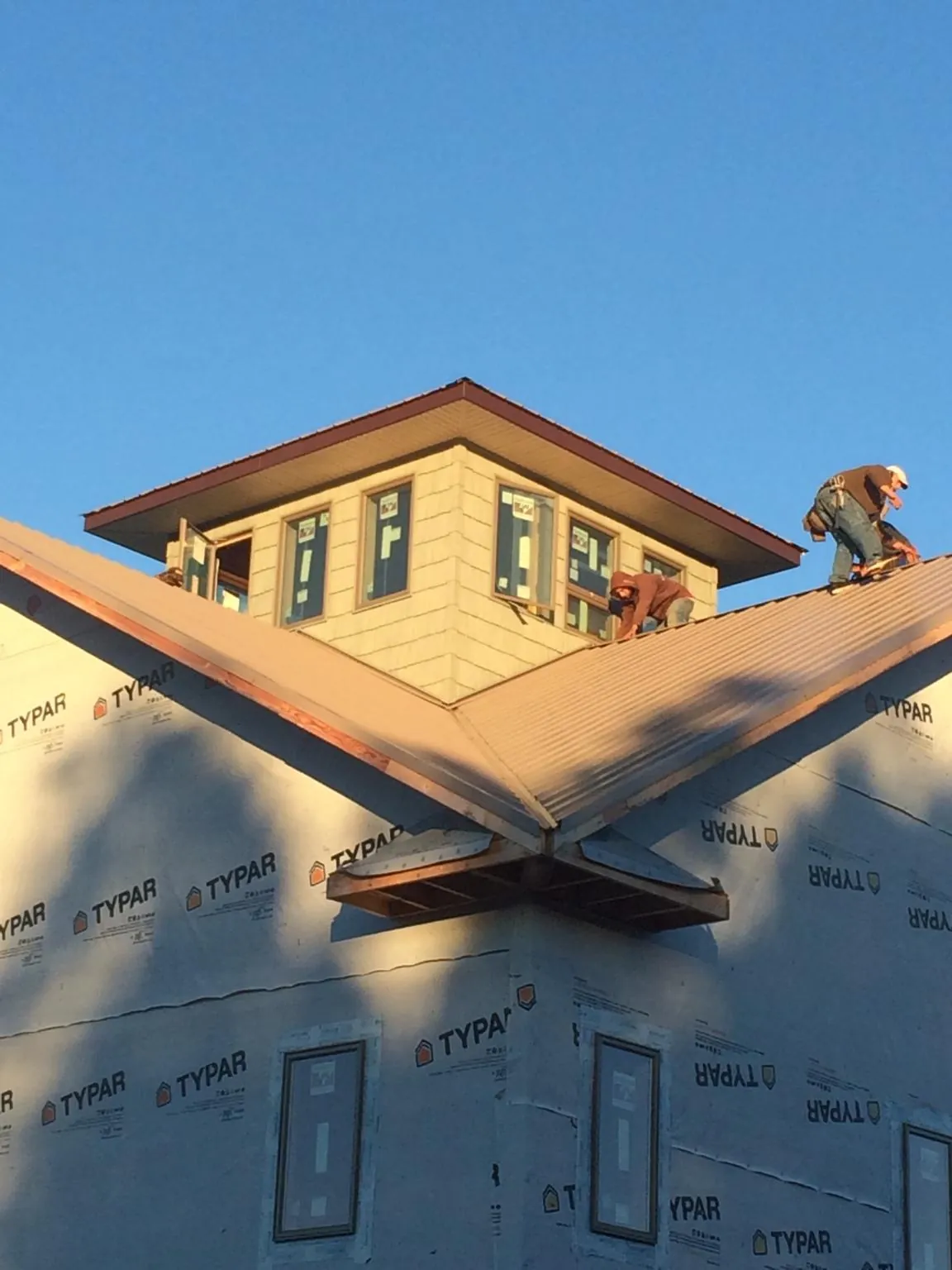 Roofers working around a rooftop cupola on a new metal roof at sunset — Roof Waterproofing in Camby by Roofing Brothers